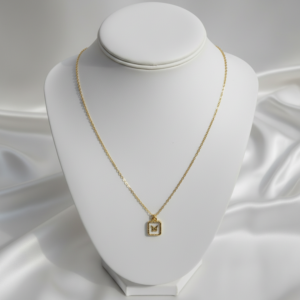 Gold necklace with a square pendant on a white mannequin bust against a white background